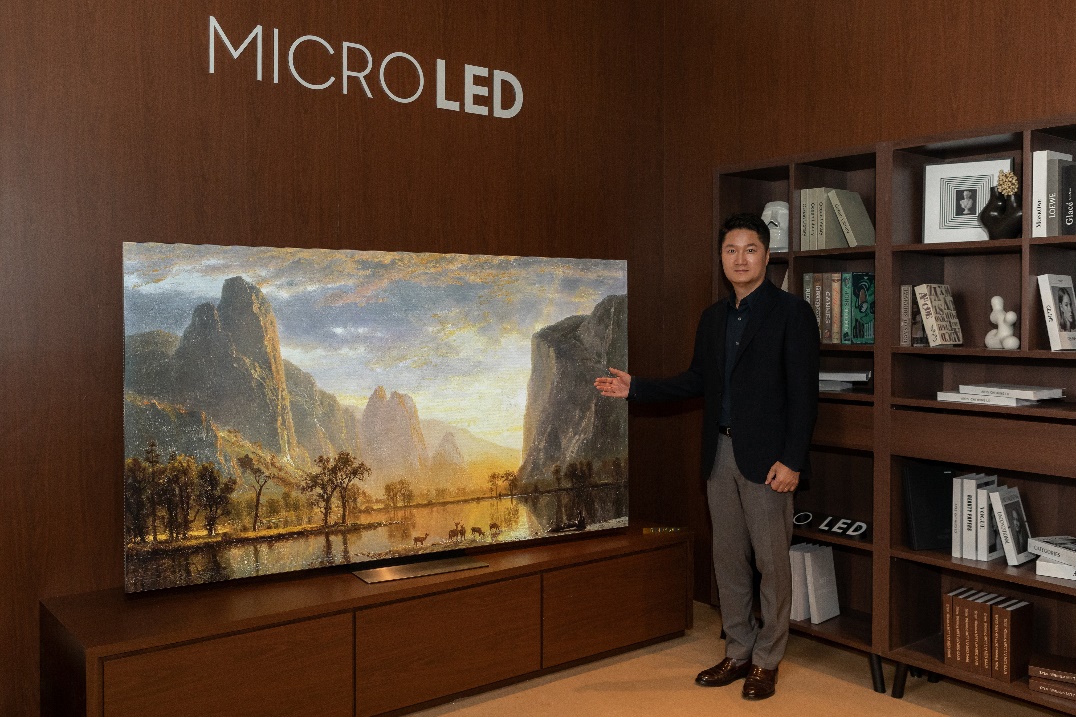 A person standing in front of a large painting Description automatically generated