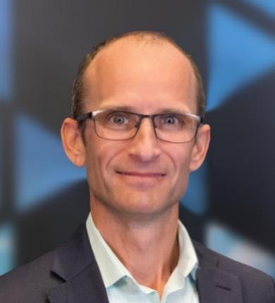 A person wearing glasses and a suit

Description automatically generated